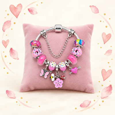 Charm-Armband mit rosa Perlen, Blumen und Schmetterling auf rosa Schmuckkissen, umrahmt von Aquarell-Herzen