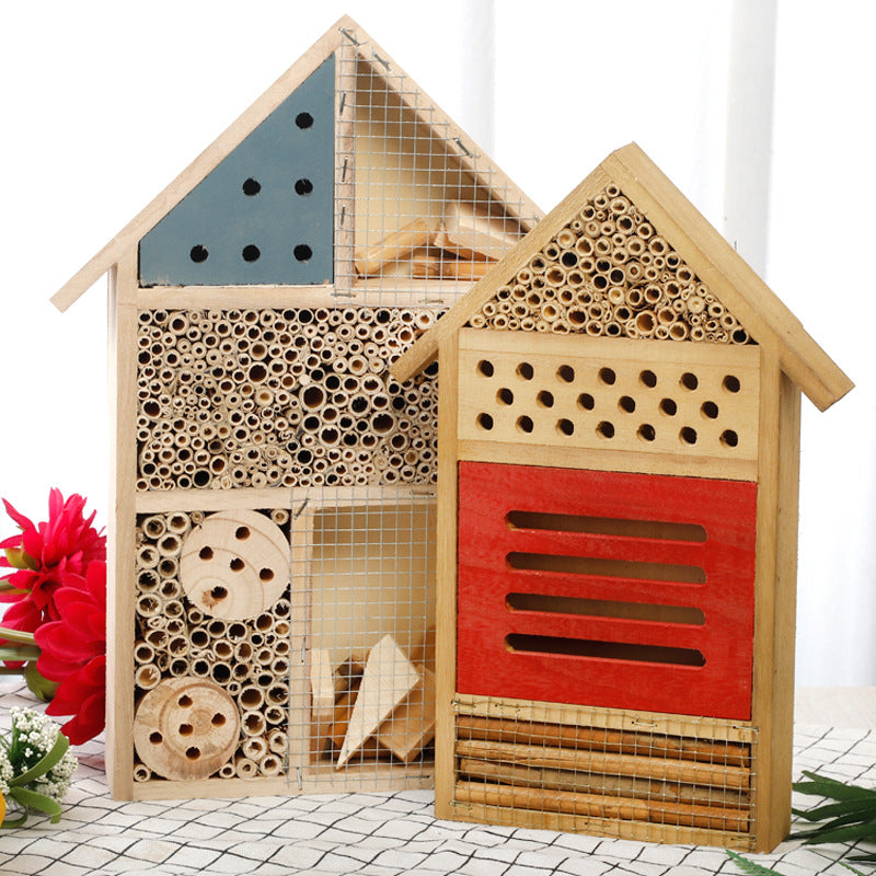 Bienenhaus aus Naturholz mit blauem Spitzdach und rotem Nistfach als Wildbienenhotel für den Garten