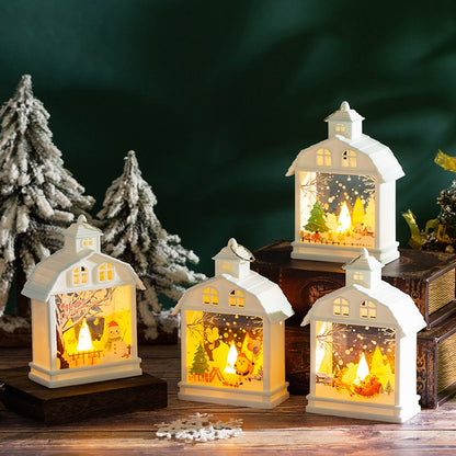 Vier weisse LED-Weihnachtslaternen als kleines Winterdorf zwischen Tannen