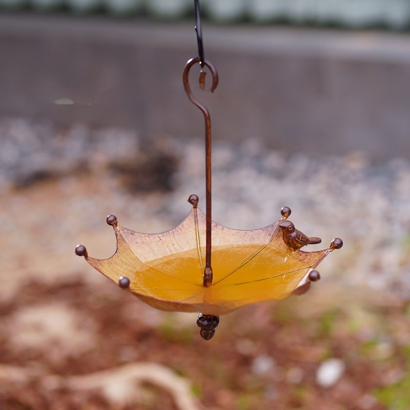 Umgedrehter Regenschirm als Vogelfutterstation aus Bronze mit geschwungenem Haken im Garten
