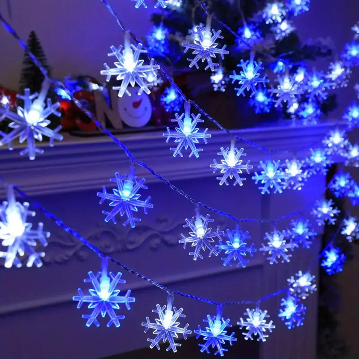 Schneeflocken Lichterkette in Weiss/Blau als Girlande über einem Kamin