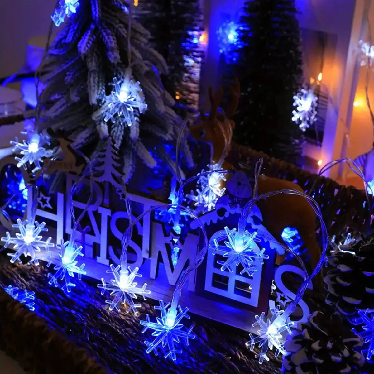 Schneeflocken Lichterkette in Weiss/Blau zwischen Weihnachtsdeko auf dem Tisch