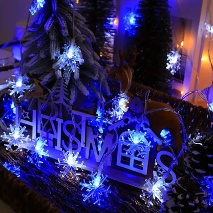 Schneeflocken Lichterkette in Weiss/Blau zwischen Weihnachtsdeko auf dem Tisch