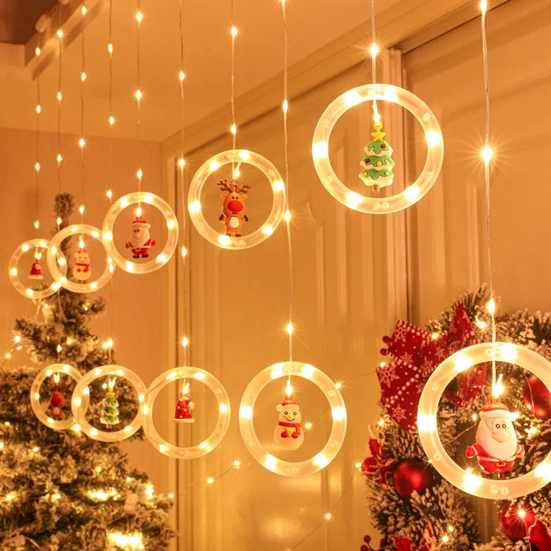 Warmweisse Ringe mit Tannenbaum- und Schneemann-Figur vor Vorhang