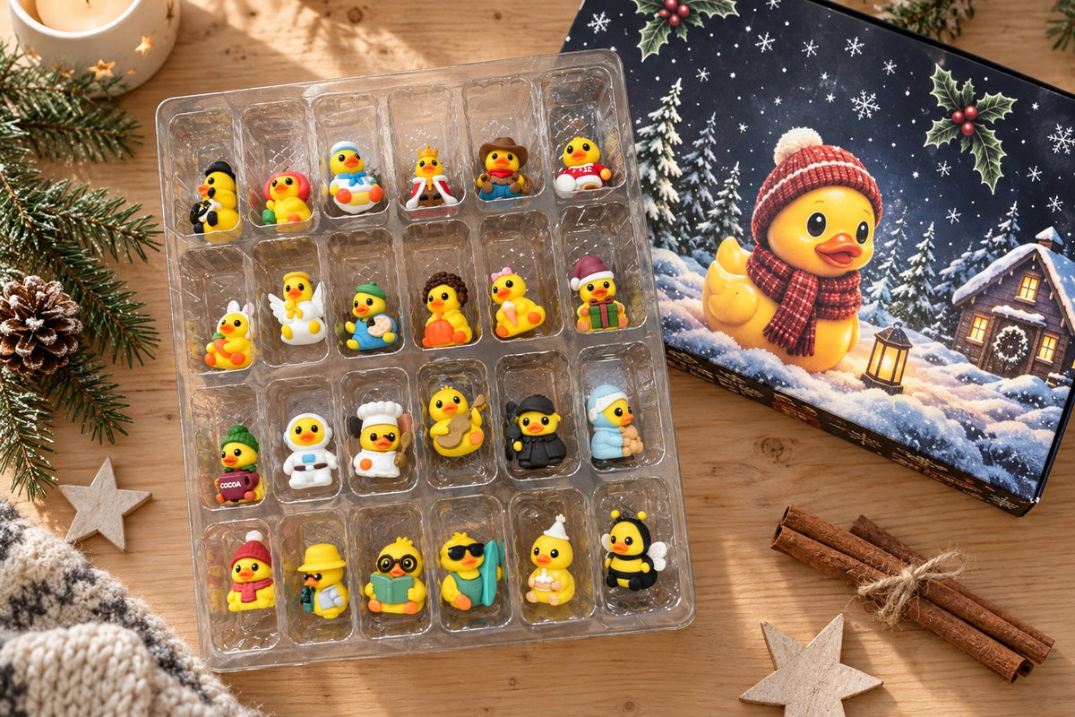 Geöffneter Adventskalender von oben: klare Schale mit allen 24 Enten-Figuren in Kostümen neben der Motivbox