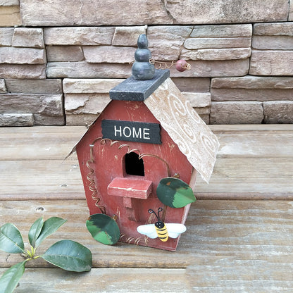 Rustikales Holz-Vogelhaus in Rot mit HOME-Schild, Biene und Steinkamin auf Holzboden