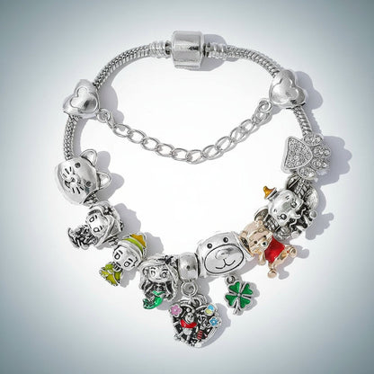 Nahaufnahme vom silberfarbenen Schlangenarmband mit Pooh-Charm, Pfote mit Glitzersteinchen und Sicherheitskette